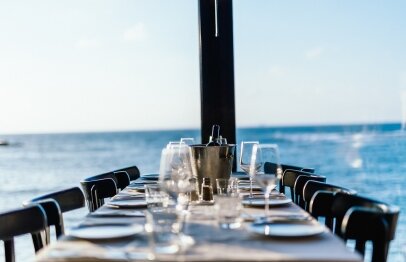 A table set with a bottle of wine along with glasses in front of the sea at Port Local Bistro
